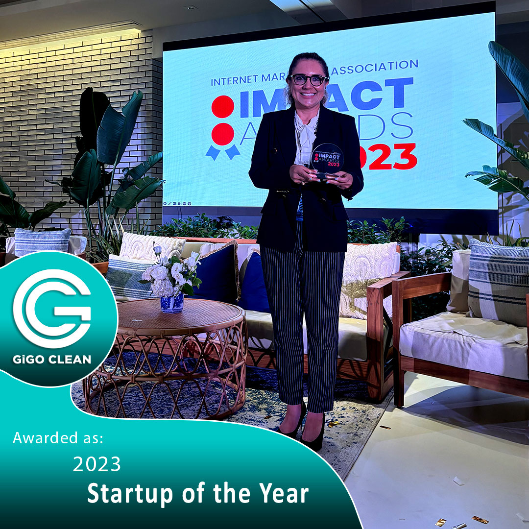 Bita Safari holding an award on stage at the IMPACT Awards 2023, with a GiGO Clean logo and 'Startup of the Year' banner in the foreground.